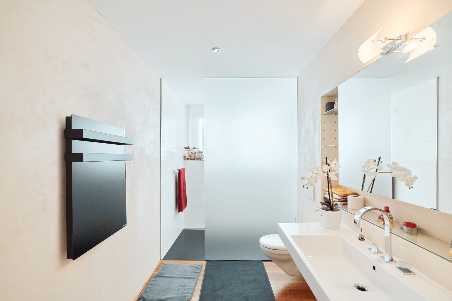 Elegante ecoQ Bagno 700+ Badezimmerheizung mit Handtuchalter in Schwarz, dezent in ein modernes Badezimmer integriert.