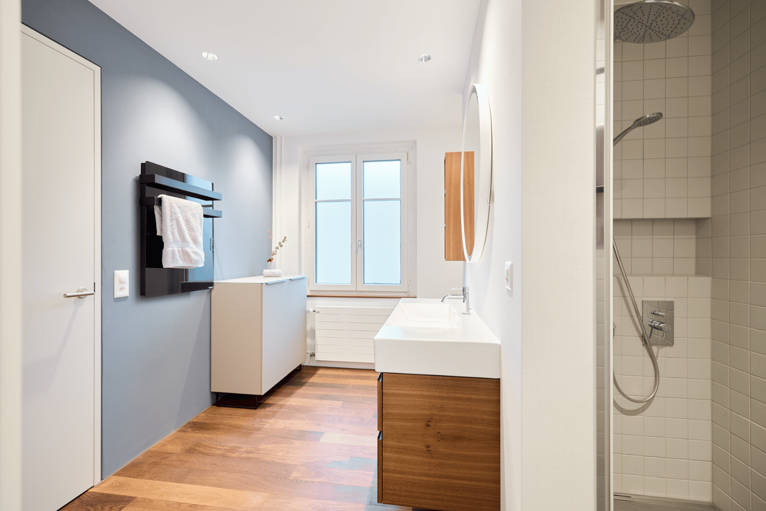 ecoQ Bagno 700+ Badezimmerheizung in Schwarz mit Handtuchalter, auf dem flauschige Handtücher hängen.