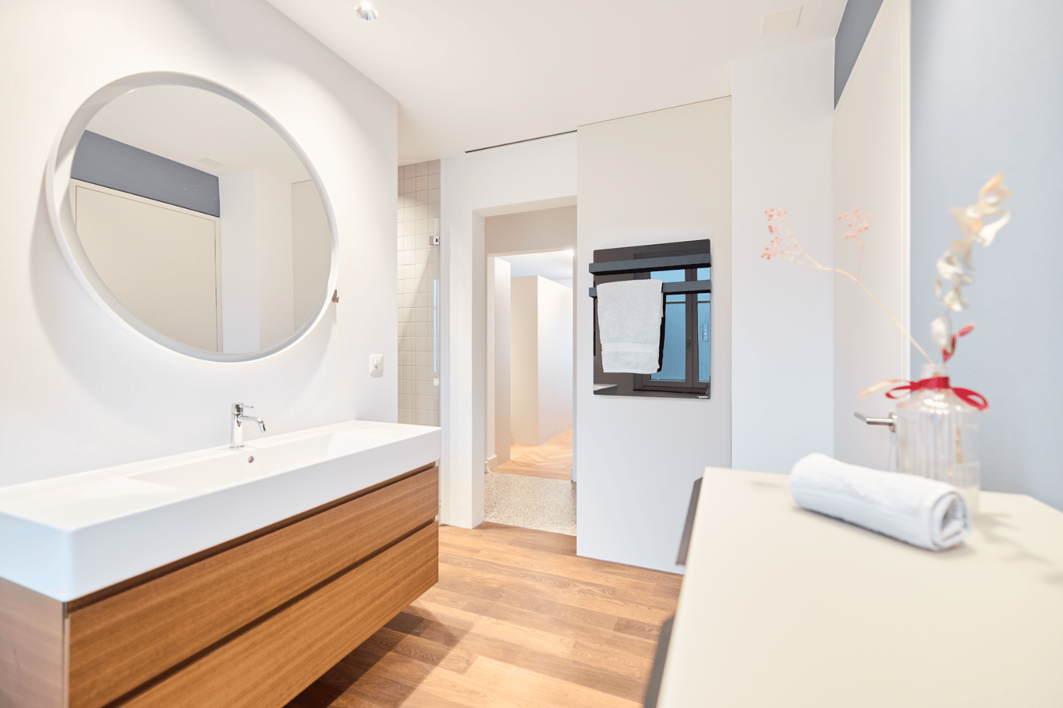 Moderne ecoQ Bagno 700+ Badezimmerheizung in Schwarz mit Handtuchalter, integriert in ein Badezimmer mit dunklen Fliesen.