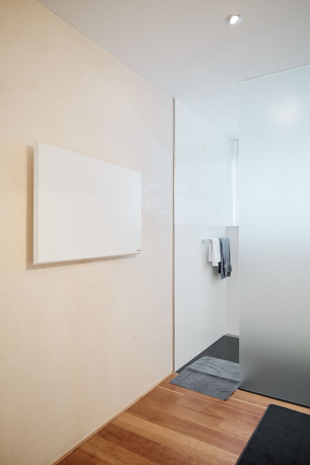 Eine ecoheat Classic-T Infrarotheizung ist an der Wand neben der Dusche montiert.