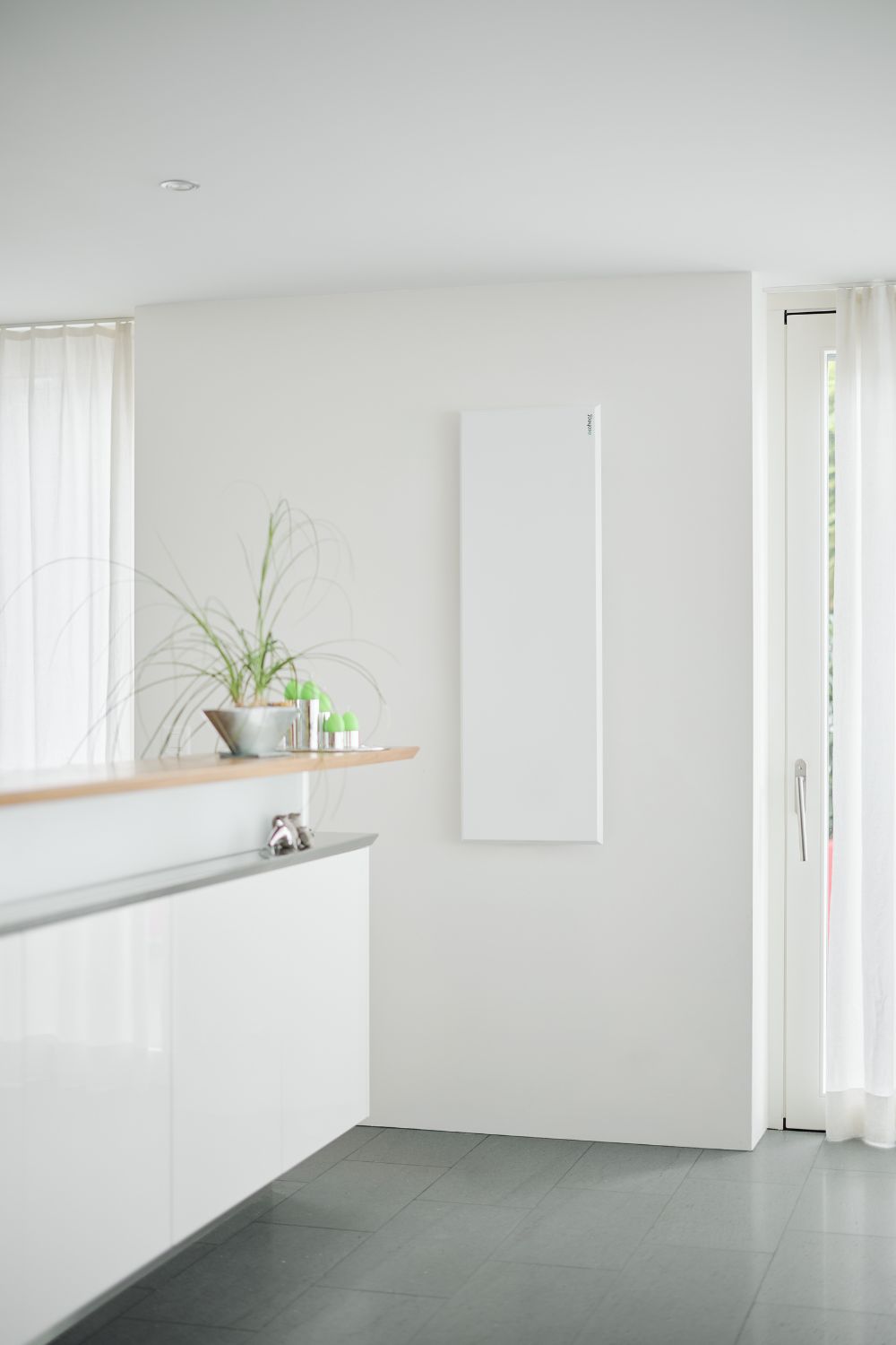 Eine ecoheat Classic-T Infrarotheizung ist an der Wand neben der Küchentheke im Wohnzimmer montiert.